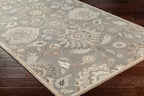 Mediterranean Seal hand-tufted wool rug with grey, taupe, and ivory floral patterns on dark wood floor.