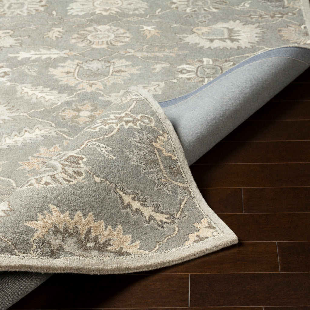Rubicon Oyster hand-tufted wool rug with grey and beige floral patterns on dark wood floor.