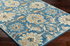 Blue Mediterranean Aegean hand-tufted wool rug with beige and orange floral patterns on dark wood floor.