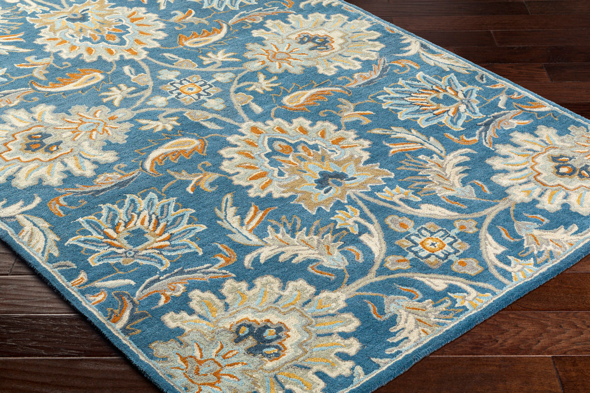 Blue Mediterranean Aegean hand-tufted wool rug with beige and orange floral patterns on dark wood floor.