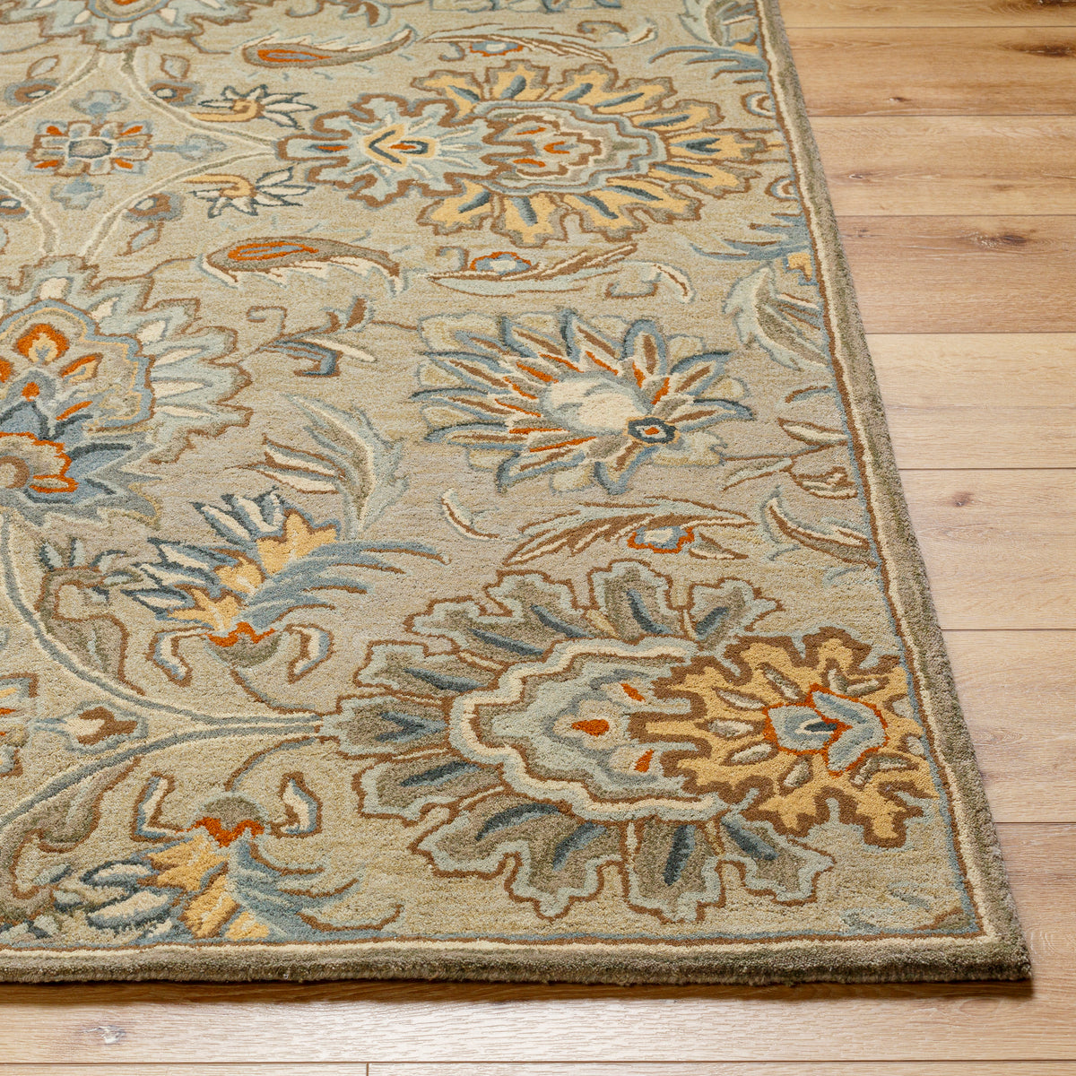 Mediterranean Pewter hand-tufted wool rug with gray, brick red, and tan floral patterns on wood floor.