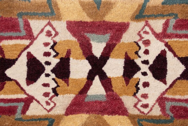 Close-up of a hand-tufted wool rug with a colorful Southwest geometric pattern.