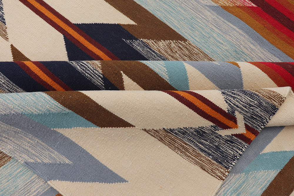 Pendleton Wyeth Trail wool rug showing a folded corner with Southwest geometric patterns in blue, red, and cream.