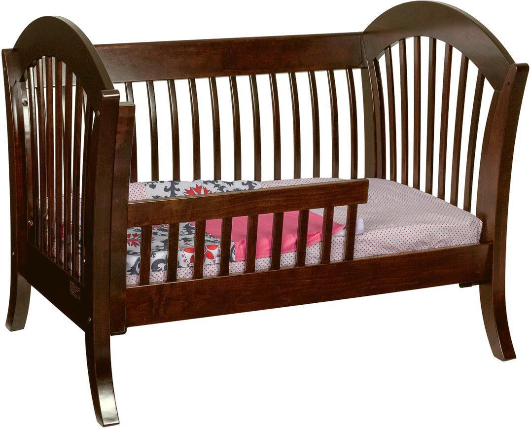 Manhattan convertible crib in dark wood, set up as a toddler bed with saber legs.