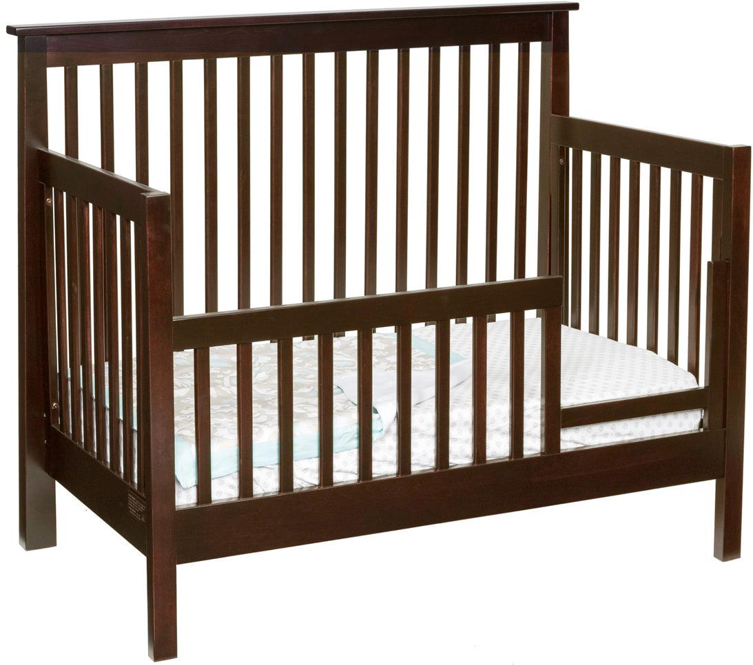 Dark brown solid maple Shaker convertible crib set up as a toddler bed with safety rail.
